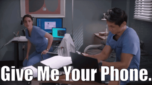 Man And Woman At Desk Saying Give Me Your Phone GIF