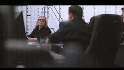 Man And Woman At Desk With Numbered Wall GIF