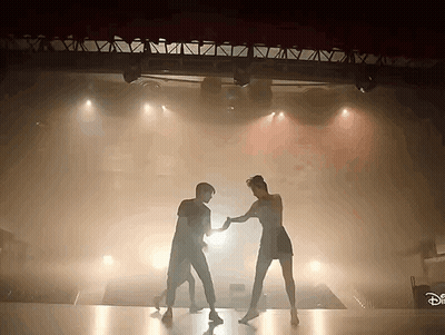 Man And Woman Dancing In Front Of Disney Sign GIF