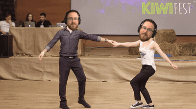 Man And Woman Dancing In Front Of Kiwifest Sign GIF