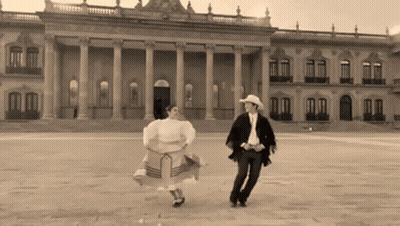 Man And Woman Dancing In Front Of Large Building GIF