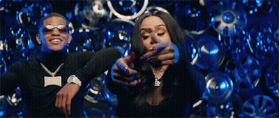 Man And Woman Dancing In Front Of Wall Of Wheels GIF