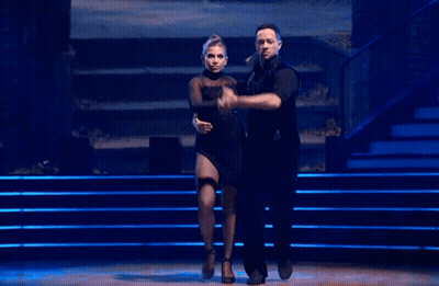 Man And Woman Dancing On Stage With Blue Lights GIF