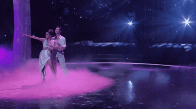 Man And Woman Dancing On Stage With Purple Smoke GIF