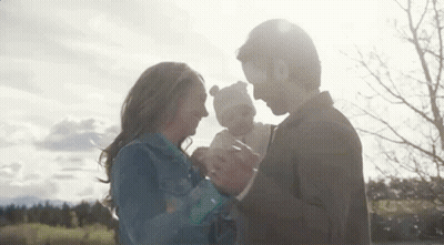 Man And Woman Holding Baby In Park GIF