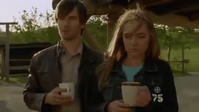 Man And Woman Holding Coffee With 75 On Jackets GIF
