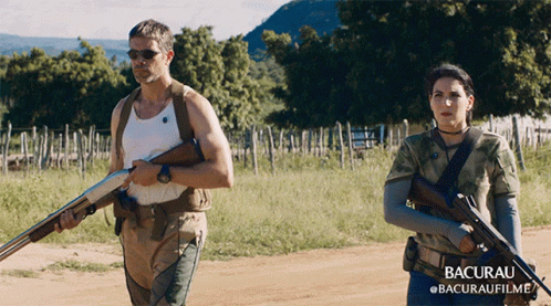 Man and Woman Holding Guns in Field Bacurau