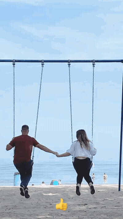 Man And Woman Holding Hands Swinging On Beach GIF