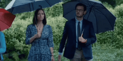Man And Woman Holding Umbrellas In Rain GIF