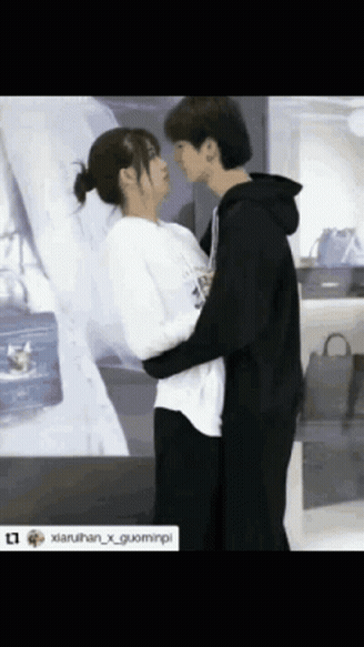 Man And Woman Hugging And Kissing In Front Of Purse Display GIF