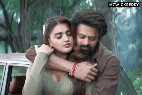 Man And Woman Hugging In Front Of 7Wickreddy Sign GIF