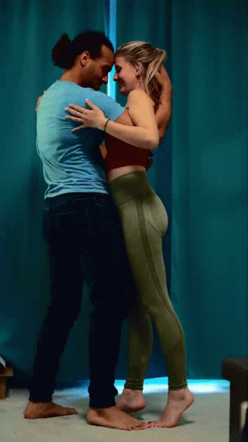 Man And Woman Hugging In Front Of Blue Curtain GIF