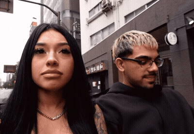 Man And Woman In Front Of Building With Chinese Characters GIF