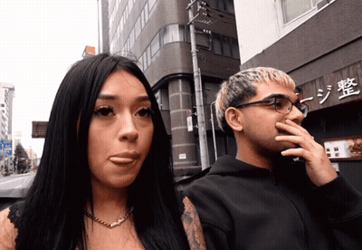 Man And Woman In Front Of Building With Chinese Writing GIF