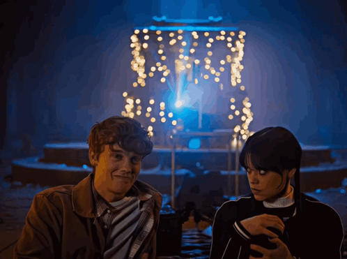 Man And Woman In Front Of Christmas Lights GIF