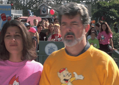Man And Woman In Front Of Disneyland Sign GIF
