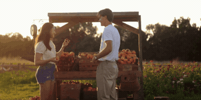 Man And Woman In Front Of Fruit Stand GIF