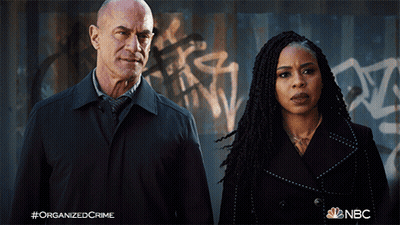 Man And Woman In Front Of Graffiti Wall Saying Organized Crime GIF