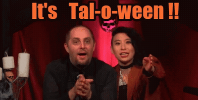 Man And Woman In Front Of It's Tal-O-Ween Sign GIF