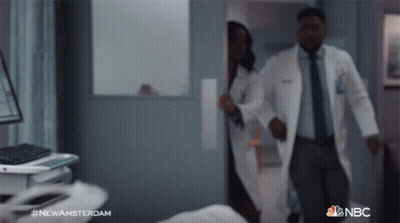 Man And Woman In Lab Coats Walking In Hospital Hallway With NBC GIF