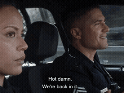 Man And Woman In Police Car Saying Hot Damn We're Back In It GIF
