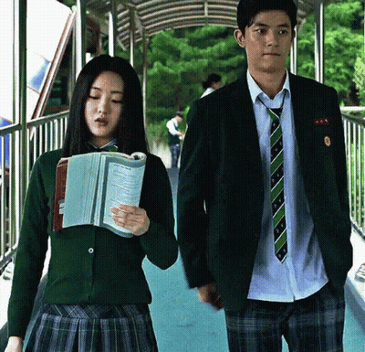 Man and Woman in School Uniforms Walking Down Bridge