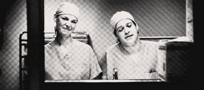 Man And Woman In Scrubs Looking Out Window GIF