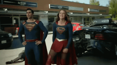 Man And Woman In Superman Costumes Standing In Front Of Store GIF