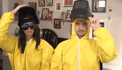Man And Woman In Yellow Suits And Welding Helmets GIF