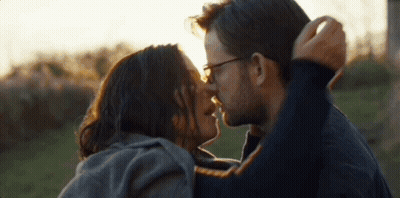 Man And Woman Kissing In Field With Sun Shining Through Eyes GIF