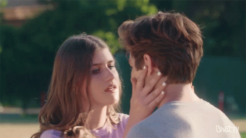 Man And Woman Kissing In Front Of Bazaar Banner GIF