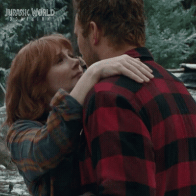 Man And Woman Kissing In Front Of Jurassic World Dominion Poster GIF