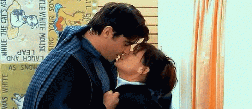 Man And Woman Kissing In Front Of Laughing Cats Sign GIF