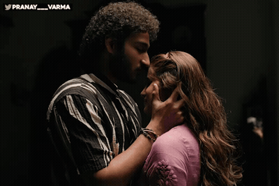 Man And Woman Kissing In Front Of Pranay Varma Banner GIF