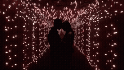Man And Woman Kissing In Room With Lots Of Lights GIF