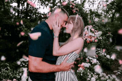 Man And Woman Kissing Under Falling Petals GIF