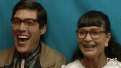 Man And Woman Laughing In Front Of Blue Wall GIF
