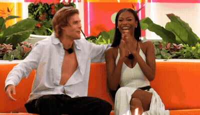 Man And Woman Laughing On Orange Couch GIF