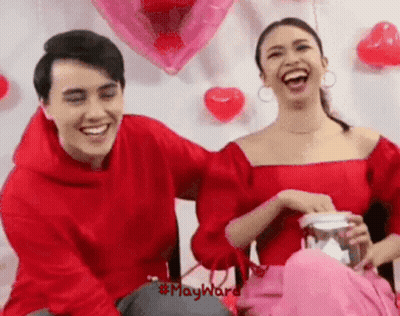 Man And Woman Laughing With Balloons And Hearts GIF