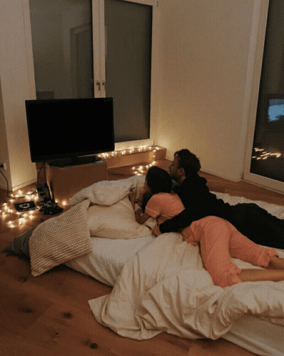 Man And Woman Laying On Bed In Front Of TV GIF