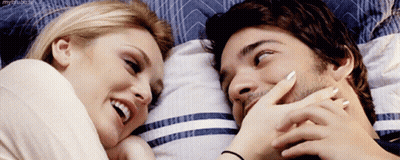 Man and Woman Laying on Bed Smiling