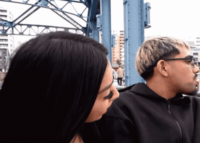 Man And Woman Looking At Each Other In Front Of Bridge GIF
