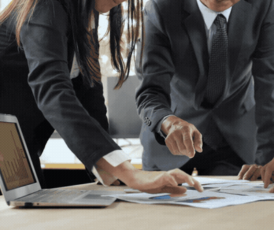Man And Woman Looking At Laptop And Papers GIF