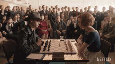 Man And Woman Playing Chess By Netflix Sign GIF