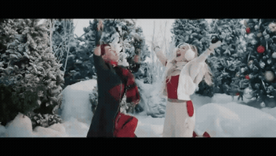 Man And Woman Playing In Snow With Christmas Trees GIF