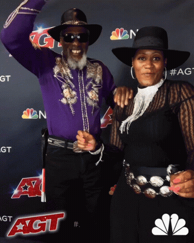 Man And Woman Posing In Front Of NBC Logo GIF