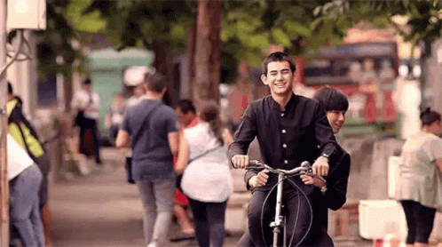 Man And Woman Riding Bike Down Street GIF