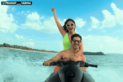 Man And Woman Riding Jet Ski With Pranay Varma Logo GIF