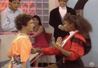 Man And Woman Shaking Hands In Front Of NBC Neon Sign GIF