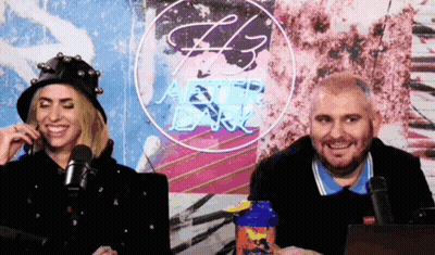 Man And Woman Sitting At Microphones Under H3 Neon Sign GIF